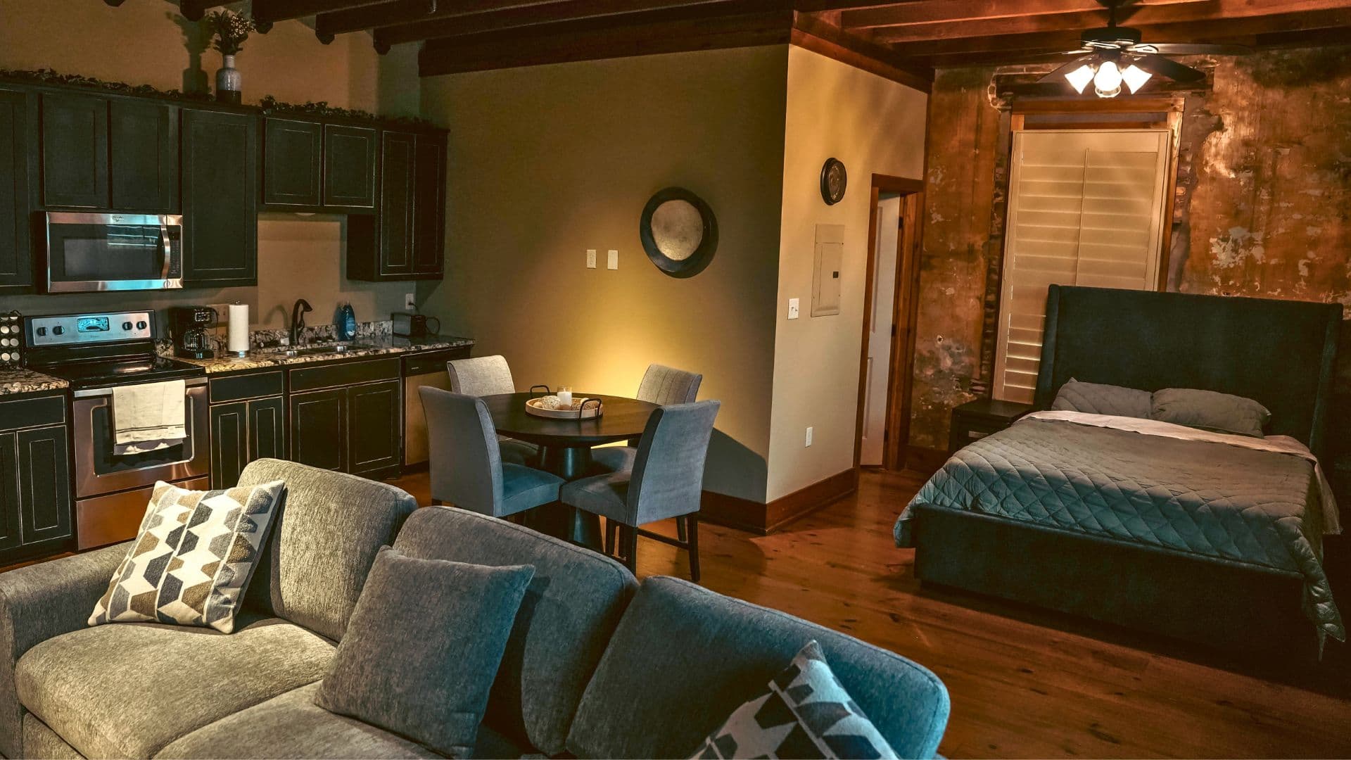 A cozy, modern studio apartment featuring a kitchen, dining area, and a bedroom with rustic accents.